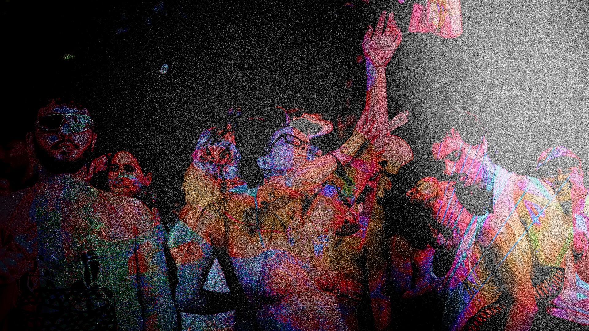 A group of people dancing closely together in dim lighting, some with their arms raised. The image has a colorful, grainy effect that gives it a vibrant, retro party atmosphere.