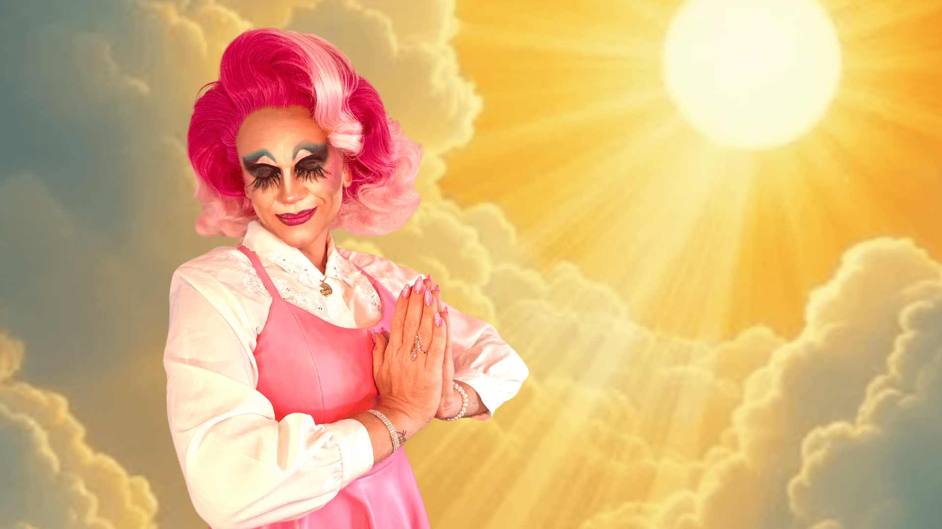A person in dramatic makeup, a pink wig, and a pink dress poses with hands together as if praying, set against a glowing sky with sunbeams shining through clouds.